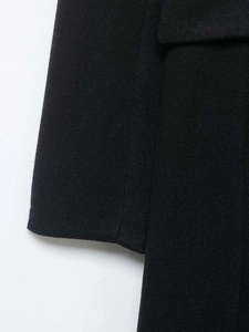 Vue macro détaillée de la texture du manteau en laine noire et des coutures de précision