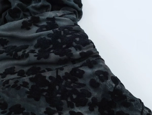 Gros plan sur un tissu en maille noire avec motifs floraux floqués et texture froncée