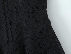 Close-up of intricate black lace fabric with hollow floral patterns and scalloped edges