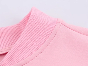 Macro detail of the light pink ribbed neckline and fine flat-lock stitching on the sweater