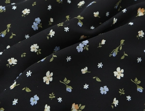 Gros plan du tissu fleuri sur une robe noire montrant de petites fleurs colorées