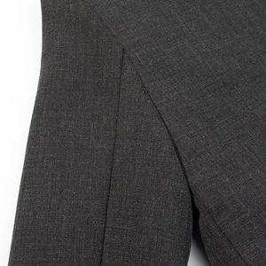 Detailed close-up showing precision stitching and slit design on charcoal grey blazer