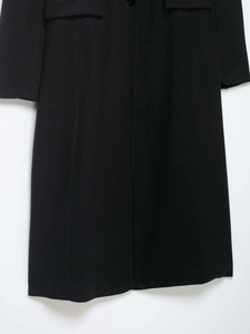 Détail du manteau noir en laine avec poches à rabat symétriques et texture de tissu raffinée