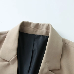 Detail of khaki blazer showing notched lapels, fine stitching, and black lining texture