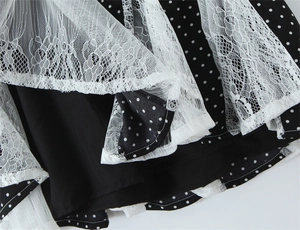 Dettaglio di tessuto a pois neri con sovrapposizione in pizzo floreale bianco su abito