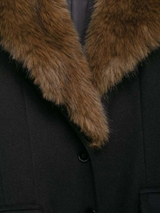 Détail d'un manteau en laine noir avec un col en fausse fourrure marron et des boutons texturés