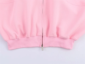 Detail view of pink knit bomber jacket showing ribbed hem and silver metal zipper