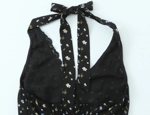 Détail de la robe noire fleurie avec col licou, bordure en dentelle et nœud élégant