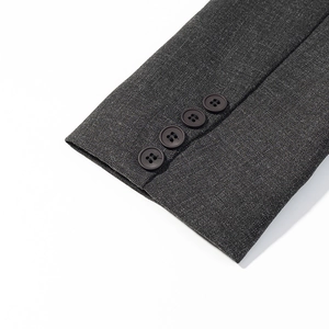 Detail of dark grey blazer sleeve with four polished resin buttons and wool texture