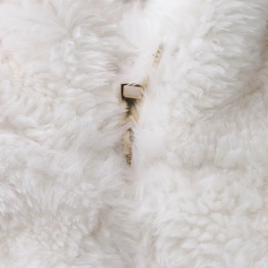 Close-up of golden metal zipper on plush white faux fur winter jacket material