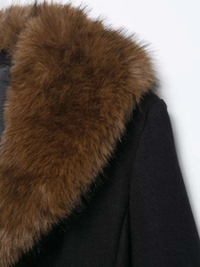 Gros plan d'un manteau en laine noir avec un col en fausse fourrure marron épais et doux