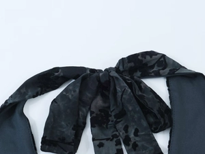 Détail du tissu en tulle floqué noir avec un élégant nœud papillon sur l'encolure
