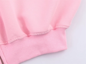 Close-up of pink knit jacket featuring ribbed cuffs and a smooth metal zipper detail
