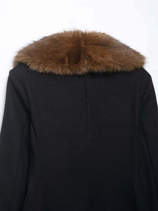 Détail d'un manteau noir avec un large col en fausse fourrure marron et couture dorsale