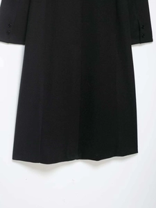 Détail d'un manteau noir en laine avec boutons décoratifs aux poignets des manches