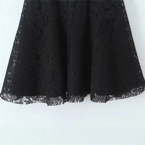 Close-up of black floral lace dress with intricate embroidery and delicate hemline detail