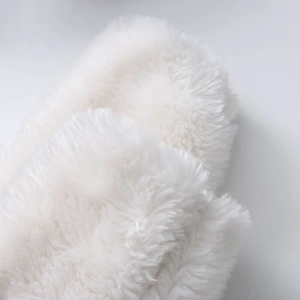 Close-up of white plush faux fur texture on a winter hooded jacket with soft fibers