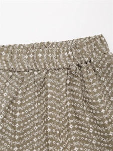 Détail macro de la taille élastique et broderie florale blanche sur short en coton vert olive
