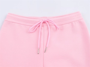 Detailed close-up of pink knit trousers with elastic waistband and metal-tipped drawstrings