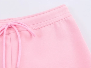 Detail view of pink knit joggers waist with elastic waistband and round drawstrings
