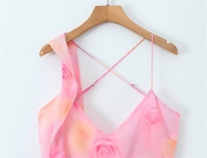 Détail de robe florale rose avec décolleté en V profond et drapé à volants sur l'épaule