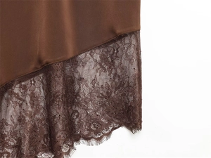 Detailed macro shot of dark brown satin fabric with intricate lace embroidery trim