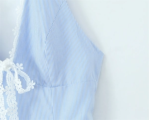 Detail of blue striped dress featuring white floral lace neckline and ribbon bow tie