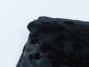 Détail du tissu en maille transparente avec flocage de velours floral noir et motifs