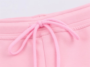Macro view of pink knitted trousers with elastic waist and matching drawstring detail