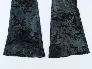 Détail du bas évasé d'un pantalon en tulle transparent avec motifs floraux floqués