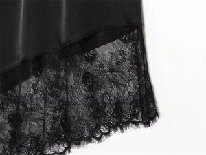 Close-up of black satin fabric with intricate eyelash lace trim and silky texture detail