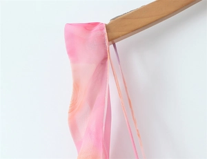Détail de l'imprimé floral pêche sur robe en mousseline avec fines bretelles et coutures