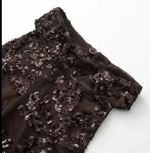 Close-up of sequin mesh fabric and round button detail on a brown halter dress