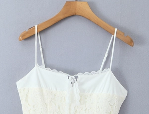 Close-up of white lace trim with a delicate bow on a floral mesh camisole top