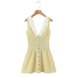 Dettaglio vestito giallo a pois con pizzo ricamato bianco e scollatura a V profonda