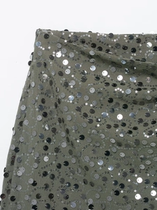 Macro detail of olive green mini skirt featuring silver and black sequin curved patterns