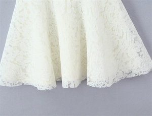 Close-up of white floral lace hem with hollow-out design and scalloped edge detail