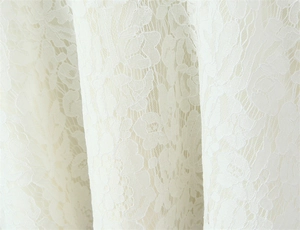 Close-up of intricate white floral lace embroidery on a sexy backless cami dress