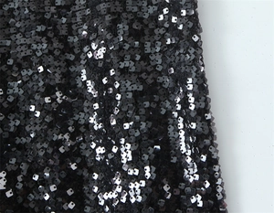 Detailed macro shot of black square sequins embroidered on elegant evening dress fabric