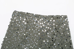 Close-up of olive green mini skirt with wavy silver sequins and metallic texture