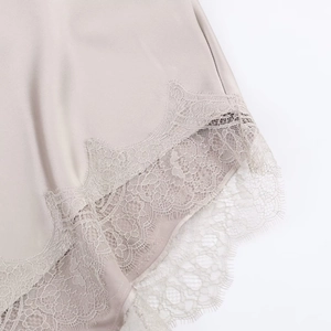 Detailed close-up of delicate eyelash lace trim on premium champagne satin fabric