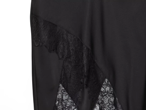 Detailed close-up of intricate black floral lace patchwork and irregular hemline texture