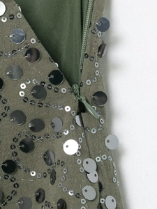 Close-up of olive green sequin fabric with silver circular metal accents and a hidden zipper