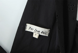 Dettaglio di cotone nero con ricamo floreale traforato ed etichetta For Love Bell