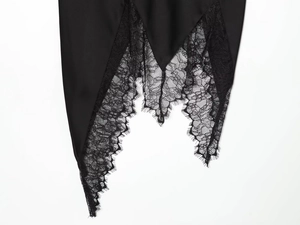 Detail of eyelash lace trim and irregular hemline on a black midi skirt fabric