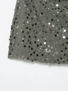Detailed macro view of sequin wave embroidery on olive green mini skirt fabric