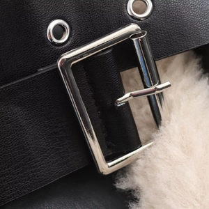 Detail of silver metal buckle and black PU leather strap with soft white faux fur lining