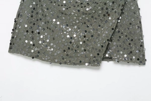 Macro shot of gray-green woven fabric with silver wavy sequin embroidery detail