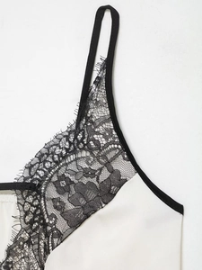 Detailansicht eines weißen Satin-Tops mit schwarzer Wimpernspitze und dünnen Trägern
