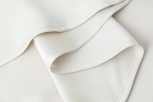 Close-up of high-quality cream satin fabric showing precise stitching and smooth seam details